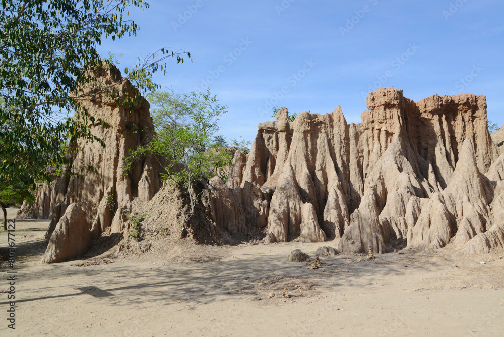 Fototapeta premium Sao Din Na Noi topography is formed from weathering and erosionare sedimentary patches that look like steep cliffs, bars, cones, recesses, and pointed peaks, emerging from the ground on an open field.