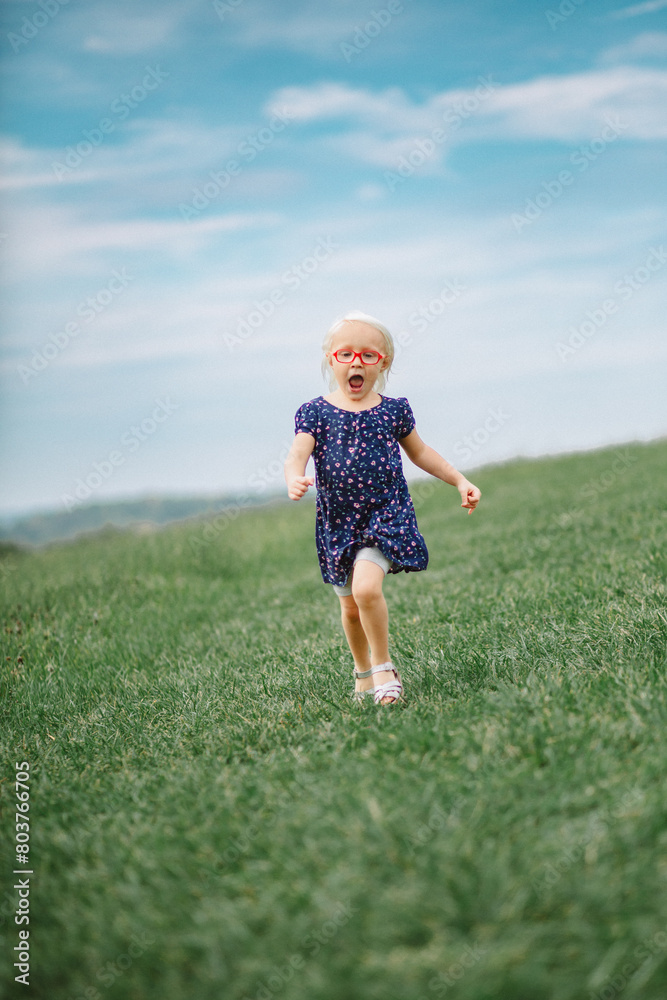 little girl with red glasses running on the field