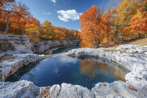 A photograph of the beautiful scenery at Games Lake State Park in Arkansas. You can see a clear blue pool surrounded by white rocks and colorful autumn foliage. Created with Ai