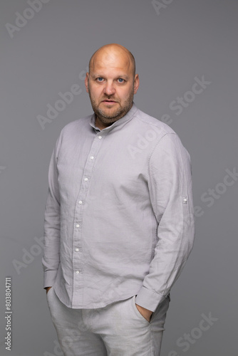 A studio portrait of a bald man in a light grey shirt, looking directly at the camera with a slight smile. © Raivo