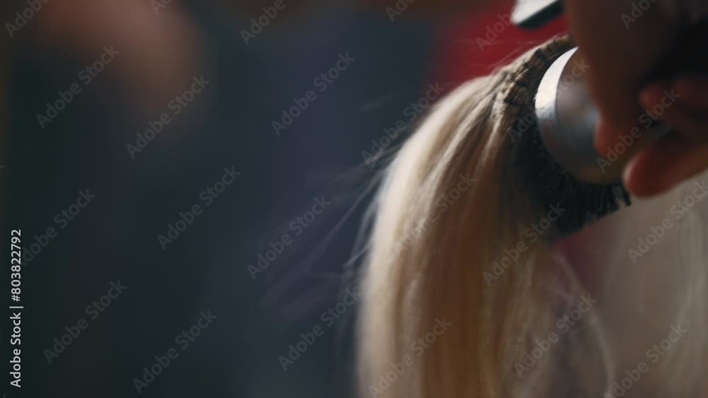 Hair stylist blow drying hair and styling it with a round brush