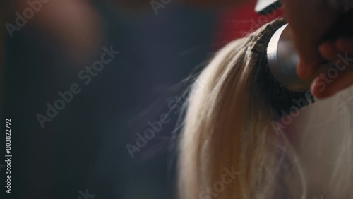 Hair stylist blow drying hair and styling it with a round brush