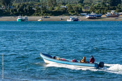 Un pescador y una compañera viajando a toda velocidad por el estero Huito, Calbuco Chile photo