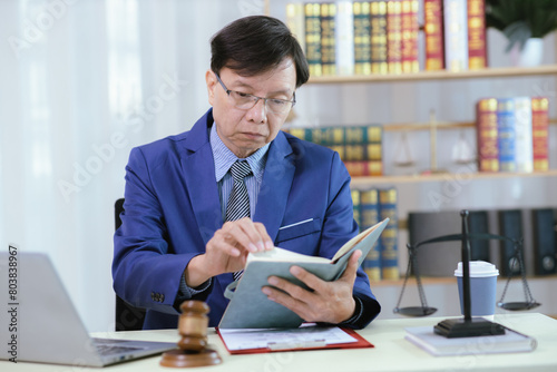 Lawyer sitting in his office On the table with a small hammer judge in court and the scales of justice The lawyer is drafting a contract for the client to sign with the defendant.