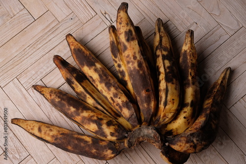 ripe bananas with black spots. served on wooden table. pisang matang. photo