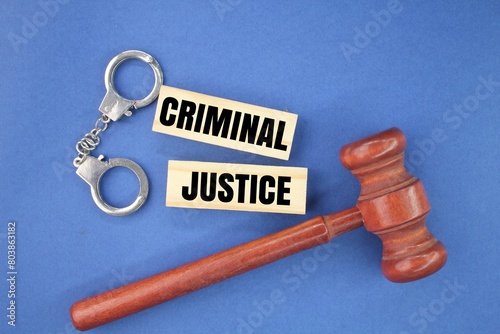 iron handcuffs and judge's gavel with the word criminal justice. the concept of court or justice