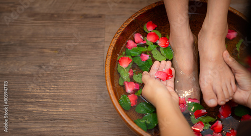 Woman soaks her feet in a bowl with flower petals