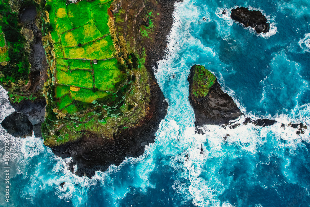 Aerial view of rough ocean with waves, volcanic beach and swiming pool in Seixal, Madeira, Portugal