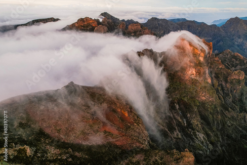 Aerial view of majestic mountain ridges at sunrise with falling fog from top of Pico do Areeiro, Madeira island, Portugal © alexanderuhrin