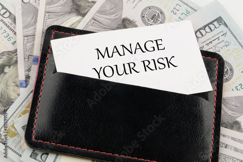 Business and manage your risk concept. Concept word Manage your risk on a business card in a leather accessory on the background of banknotes photo