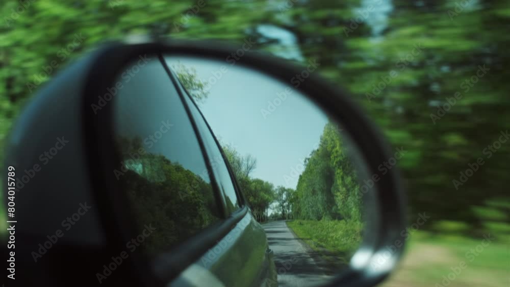 Reflection in mirror of car driving through spring landscape in faraway travel destination at sunny day. Beautiful travelling wanderlust inspiration and adventure concept
