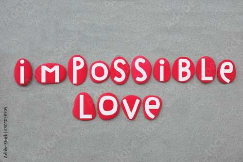 Impossible love, creative phrase composed with hand painted red colored stone letters over green sand