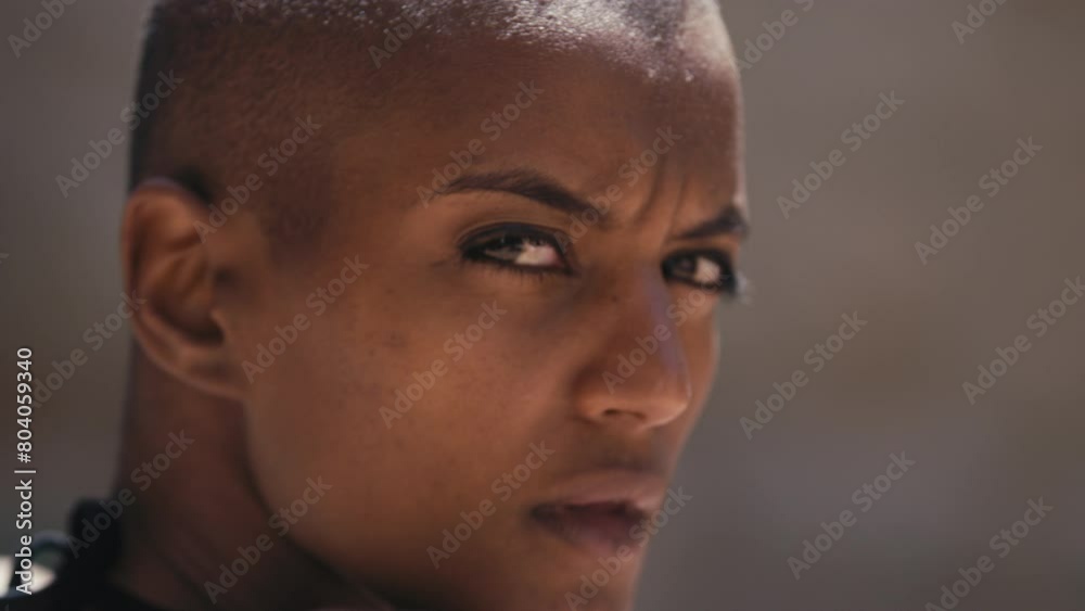 Woman with shaved head looks over shoulder at camera Woman with shaved head looks over shoulder at camera