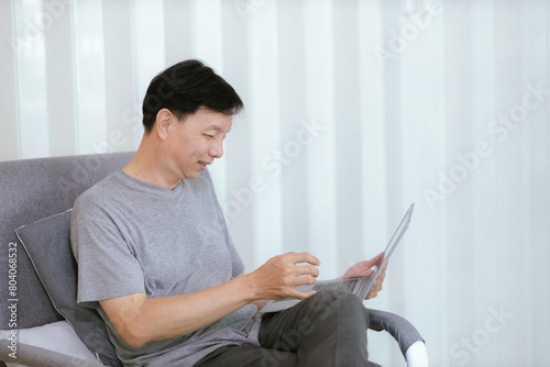 Smiling old man talking over smartphone while relaxing at home. Senior man after retirement using smart phone to connect with friends and family.