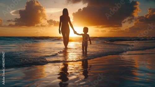 A silhouette of a mother and child holding hands at a sunset beach