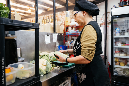 Obraz na plátně Female Chef Preparing Fresh Vegetables in a Professional Kitchen Setting