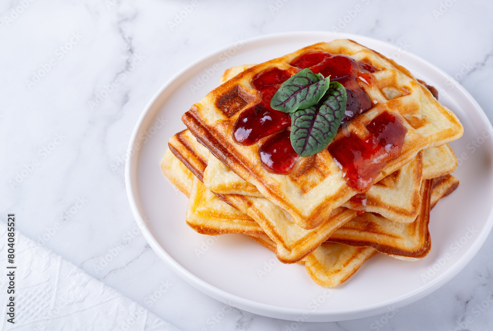 Belgian waffles with strawberry jam on a white background