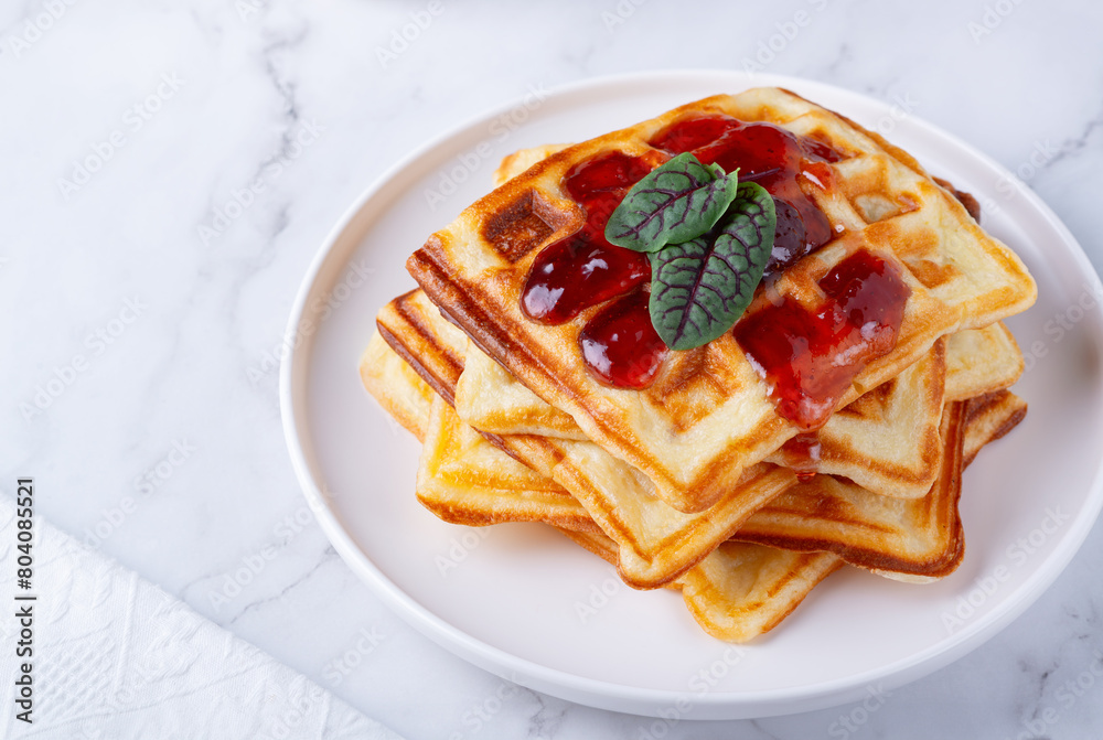Belgian waffles with strawberry jam on a white background Belgian waffles with strawberry jam on a white background