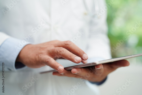 Asian man doctor using tablet computer to reading patient report  check up and search for solve treatment health medical online in hospital.