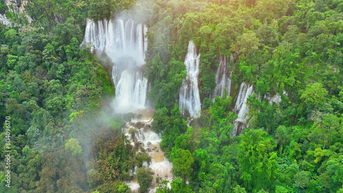 The emerald-green surroundings, the hidden grand waterfall in the heart of the tropical rainforest is a breathtaking sight captured from above by a drone. Vivid forest: Earth's wild art. Thailand.
