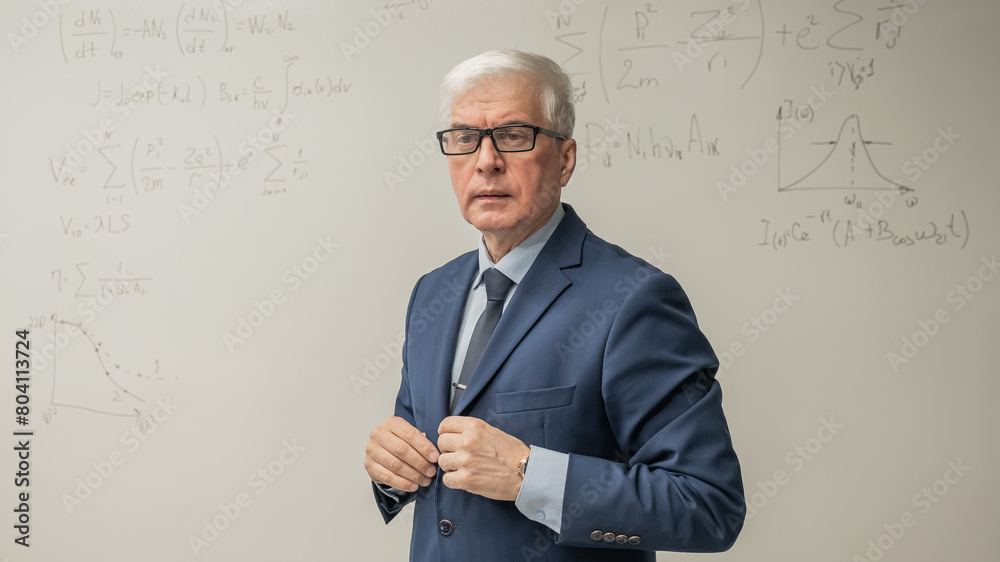 Mature man stands at a white board with written formulas. Mature man stands at a white board with written formulas.