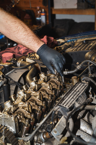 The mechanic is repairing a car engine. Cylinder head. Valve. Sixteen valves. Valve springs. Engine block. Rocker shaft. Rocker arm. Car repairing. Auto service.