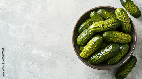 Bowl of tasty pickled cucumbers on light background