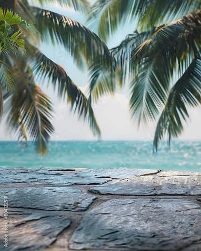 Close up of a stone table top with palm trees and ocean in the blurred background 
