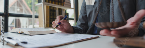 A lawyer or legal advisor prepares to sign legal contract documents. Managing a business with one hand and weighing it with a scale to determine the results of the analysis  principles of legality.