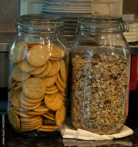 Glass jars, one with cereal and the other with cookies.