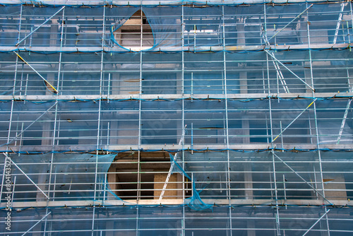 Photo of scaffolding with blue safety netting on a large building during construction work on the building