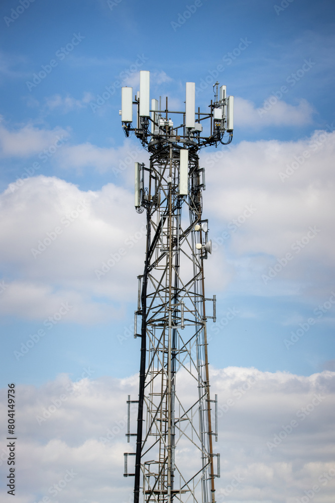 Photo of a mobile telephone communications tower on a sunny summers day with white clouds in the sky Photo of a mobile telephone communications tower on a sunny summers day with white clouds in the sky