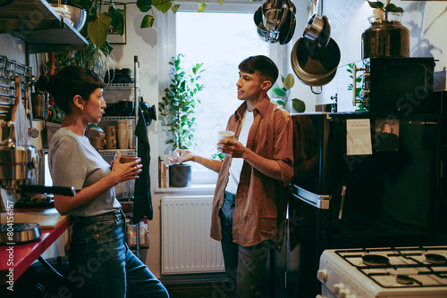 Young male and female freelancers discussing in kitchen during coffee break at home office photo