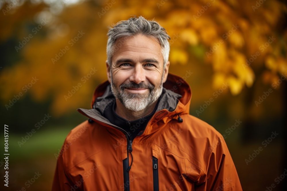 Portrait of a happy man in his 40s wearing a functional windbreaker in background of autumn leaves Portrait of a happy man in his 40s wearing a functional windbreaker in background of autumn leaves