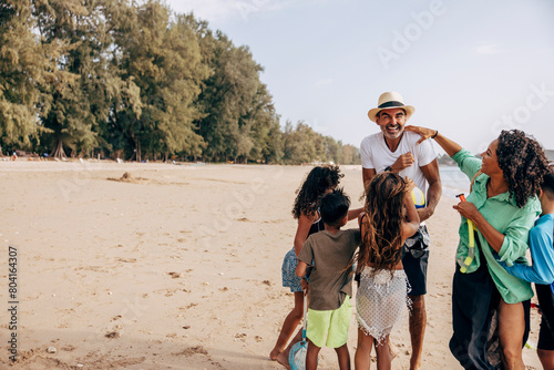 Playful family ticking man while standing on sand at beach during vacation