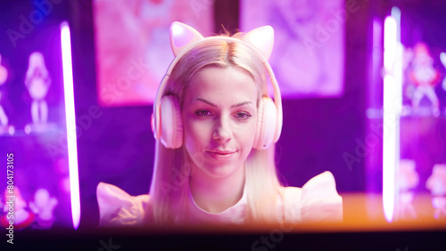 Maid girl gamer with cat ear headphones looking at the monitor