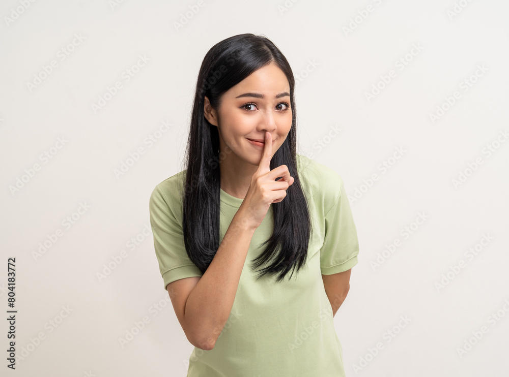 Happy beautiful young asian woman whispering some secret gossip. Excited pretty latin girl index finger on mouth standing pose on isolated white background. Happy beautiful young asian woman whispering some secret gossip. Excited pretty latin girl index finger on mouth standing pose on isolated white background.