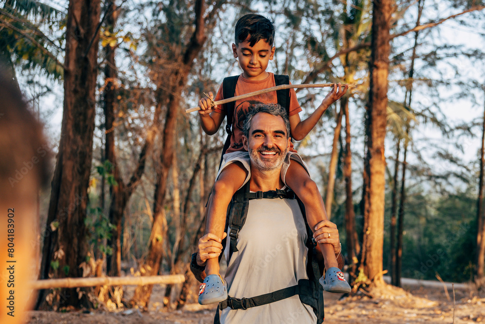 Portrait of happy father carrying son on shoulders in forest Portrait of happy father carrying son on shoulders in forest