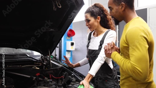 Young female auto mechanic explaining to her customer what needs to be fixed in his car photo