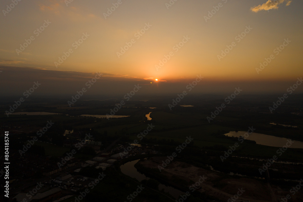 Obraz premium Aerial photo of the beautiful sun setting over the town of Castleford in the district of Wakefield in the UK, showing roof top view of typical British UK rows of houses and streets.