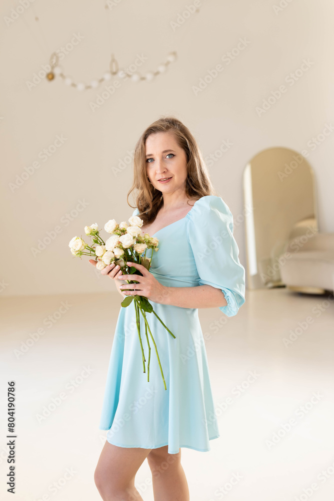 Young attractive blonde woman in blue dress holding white roses.. Young attractive blonde woman in blue dress holding white roses..