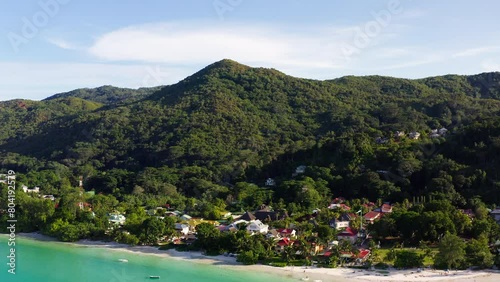 Drone shot unveils the stunning coastline of Praslin Island. Dozens of boats parked near the shore. Mountainous island in the Indian Ocean. Seychelles, Africa Anse Volbert beach, holiday destination photo
