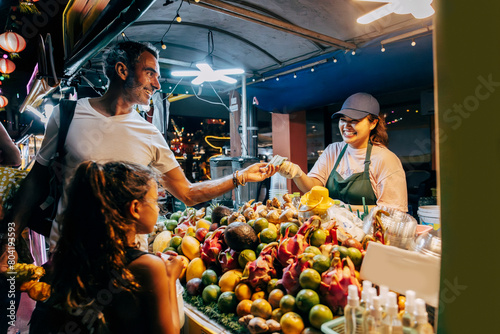 Smiling man paying for juice while standing at stall in food market
