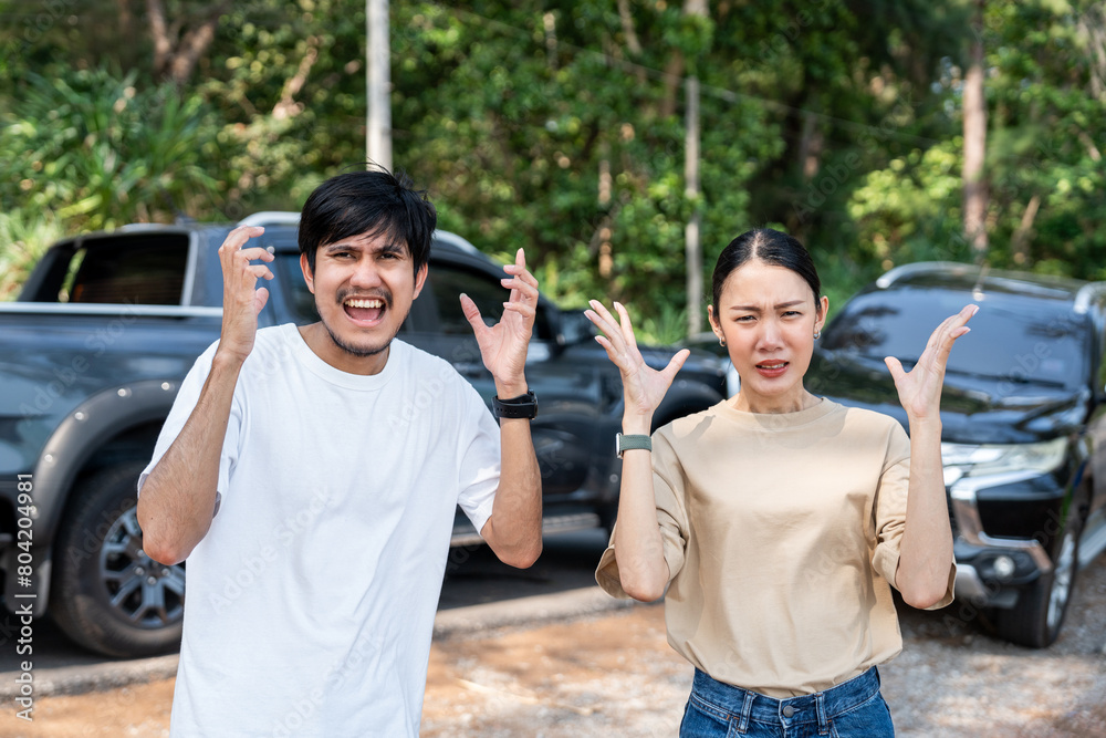 Obraz premium Asian man and woman drivers arguing after traffic collision accident feeling serious and stressed. Parked on side way road Call Emergency assistance or insurance claim service. Car Crash