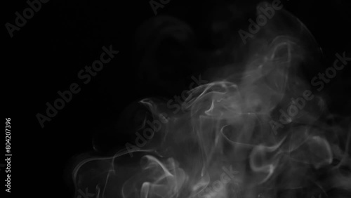 a heavy smoke trail being reduced to a small smoke trail isolated on a black background photo