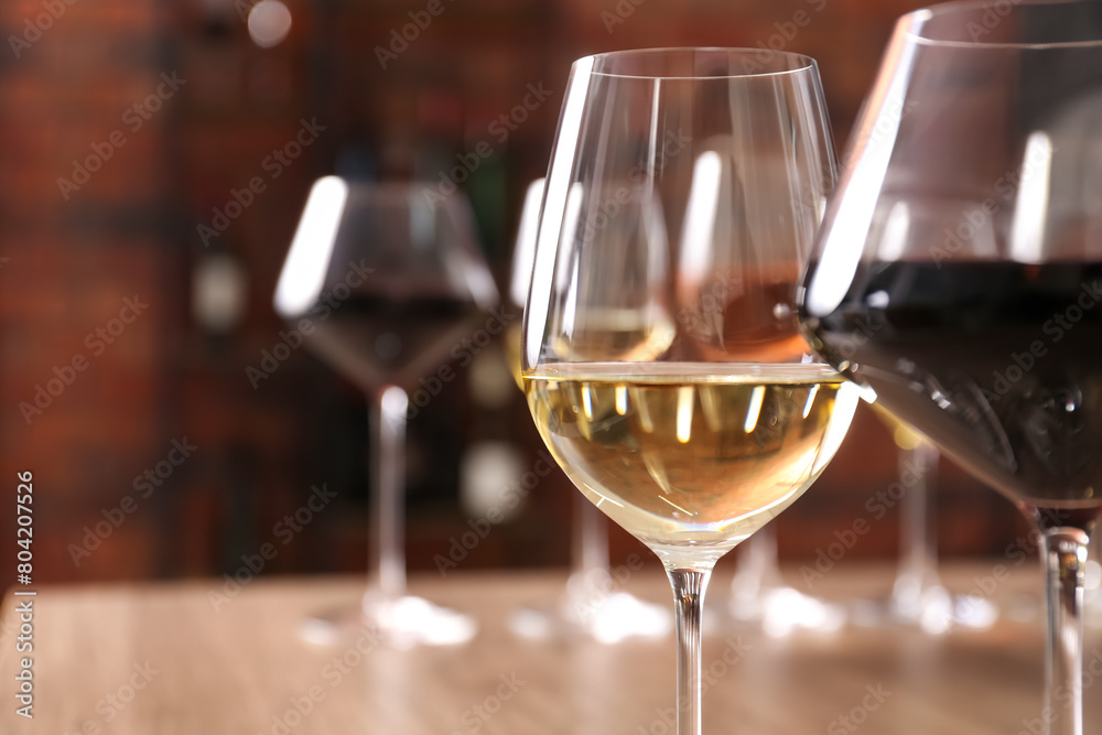 Tasty red and white wines in glasses against blurred background, space for text Tasty red and white wines in glasses against blurred background, space for text