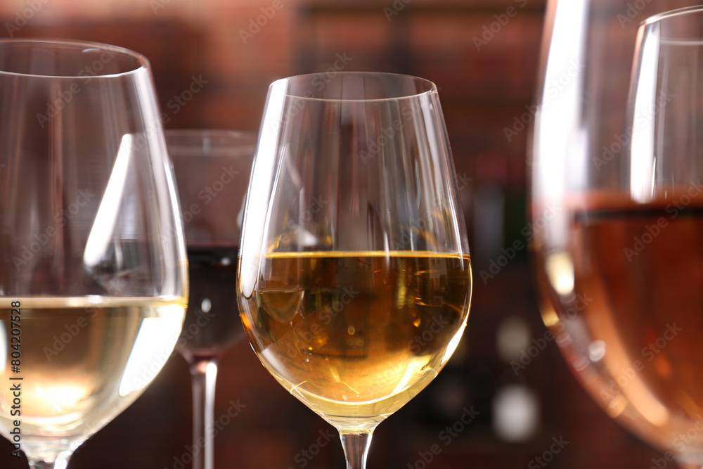 Different tasty wines in glasses against blurred background