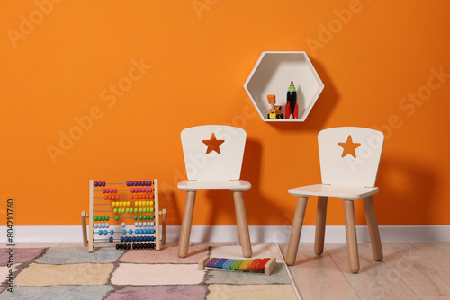 Beautiful children's room with bright orange wall and furniture. Interior design photo