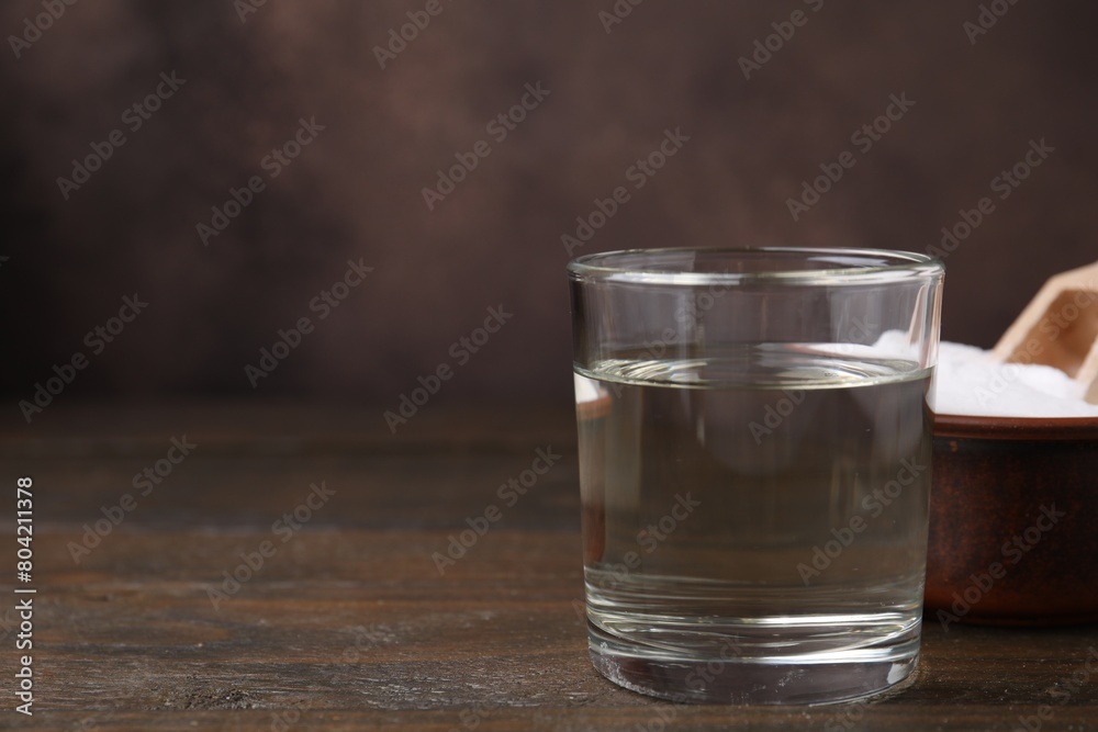 Vinegar in glass and baking soda on wooden table, space for text Vinegar in glass and baking soda on wooden table, space for text