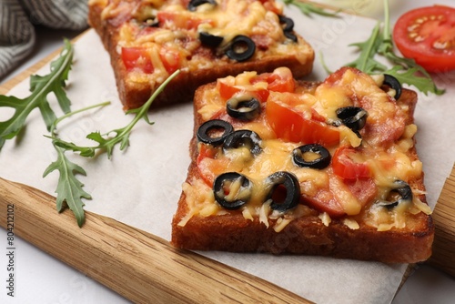 Tasty pizza toasts and ingredients on white table, closeup